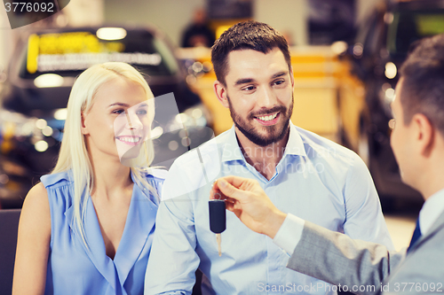 Image of happy couple with car dealer in auto show or salon