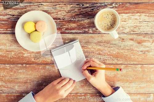 Image of close up of hands, notebook, coffee and cookies