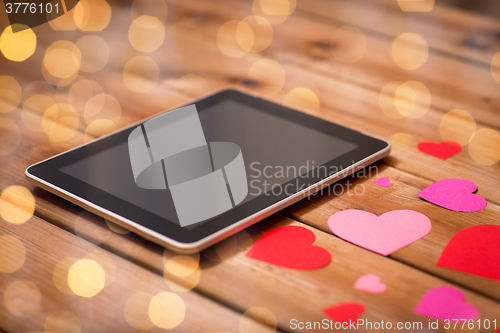 Image of close up of tablet pc and hearts on wood