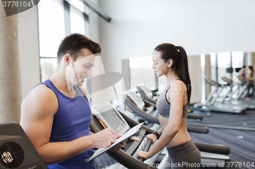 Image of happy woman with trainer on treadmill in gym