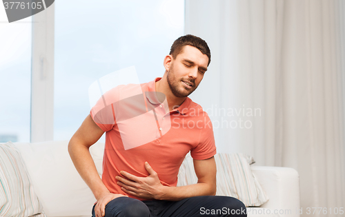 Image of unhappy man suffering from stomach ache at home