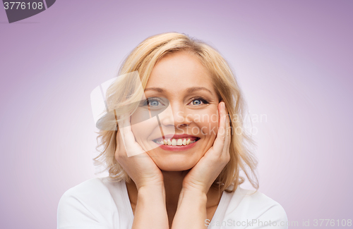 Image of smiling woman in white t-shirt touching her face