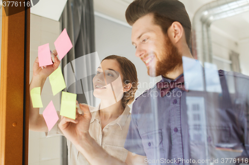 Image of happy creative team writing on stickers at office