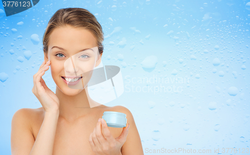 Image of happy young woman applying cream to her face