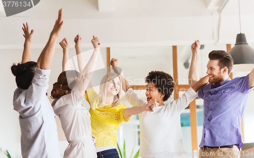 Image of happy creative team celebrating victory in office