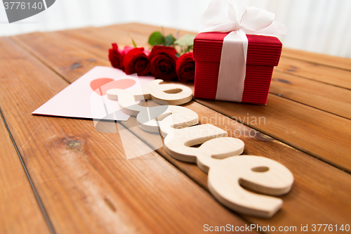 Image of close up of gift box, red roses and greeting card