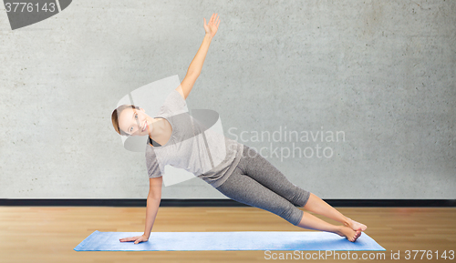 Image of woman making yoga in side plank pose on mat