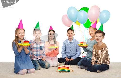 Image of happy children in party hats with birthday cake