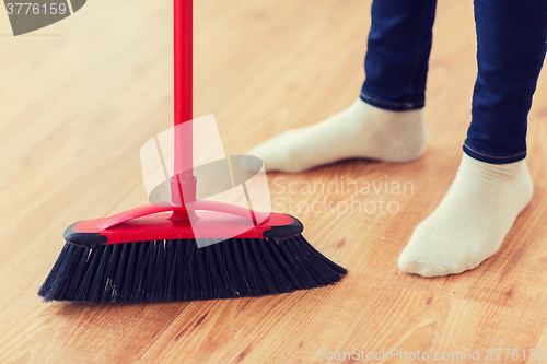 Image of close up of woman legs with broom sweeping floor