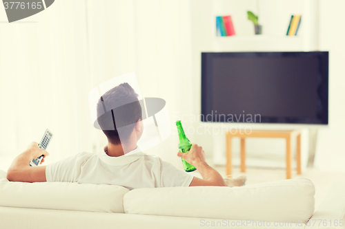 Image of man watching tv and drinking beer at home