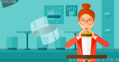 Image of Woman eating hamburger. 