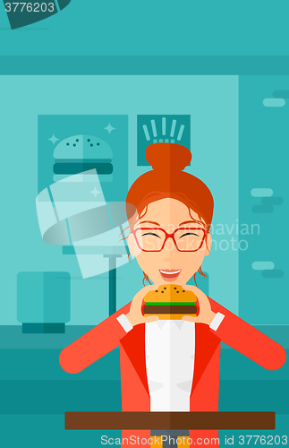 Image of Woman eating hamburger. 