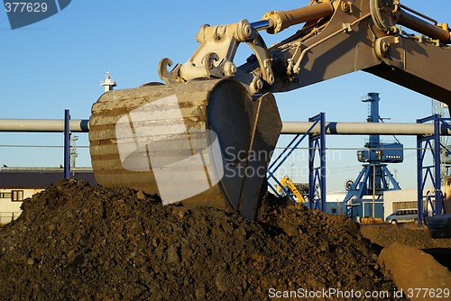 Image of Hydraulic excavator at work. Shovel bucket against blue sky