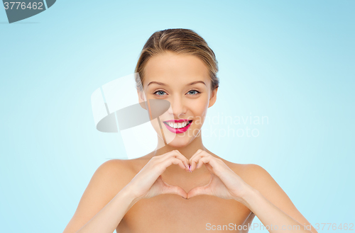 Image of smiling young woman showing heart shape hand sign