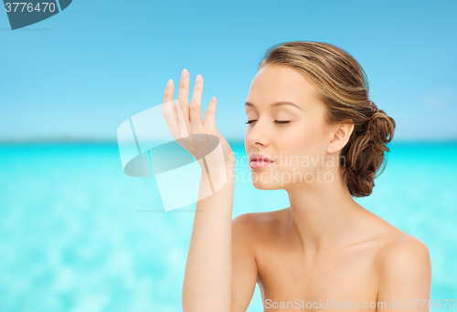 Image of woman smelling perfume from wrist of her hand