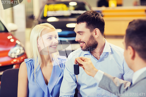 Image of happy couple with car dealer in auto show or salon