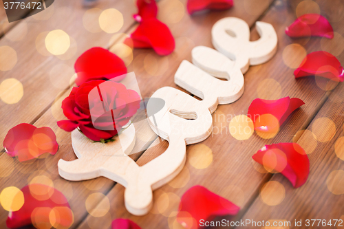 Image of close up of word love cutout with red rose on wood