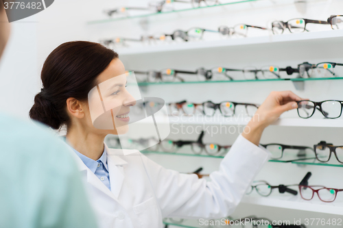 Image of optician showing glasses to man at optics store