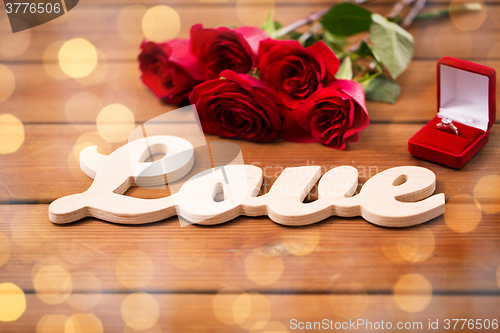 Image of close up of diamond ring, red roses and word love