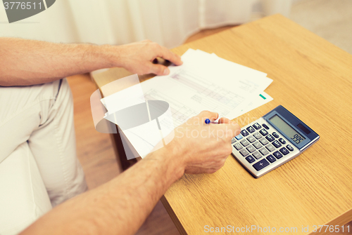 Image of close up of man with papers and calculator at home