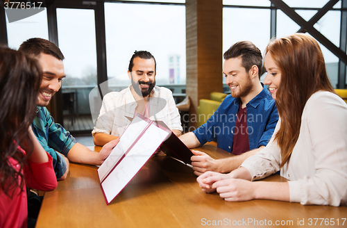 Image of smiling friends discussing menu at restaurant