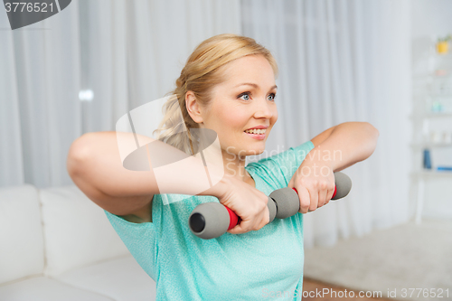 Image of woman exercising with dumbbells on mat at home