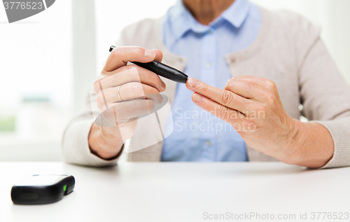 Image of senior woman with glucometer checking blood sugar