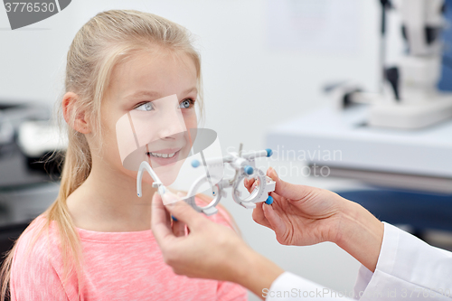 Image of optician with trial frame and girl at clinic