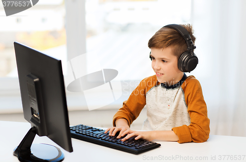 Image of happy boy with computer and headphones at home