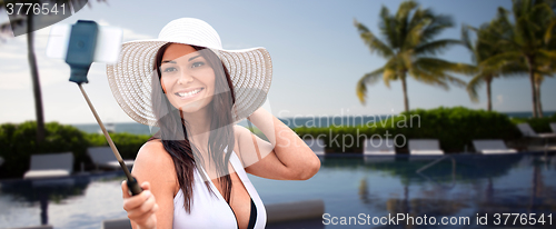 Image of smiling young woman taking selfie with smartphone