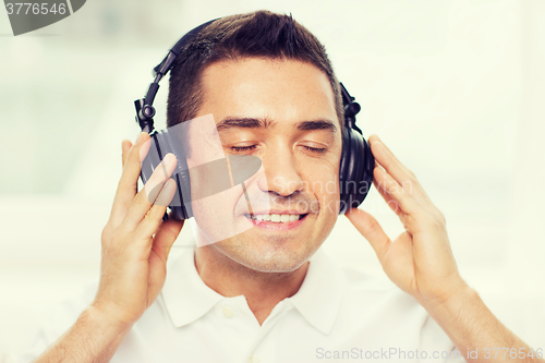 Image of happy man in headphones listening to music at home