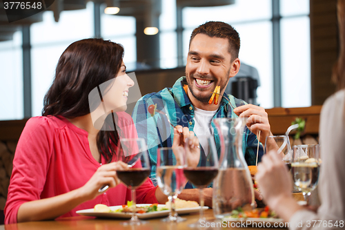 Image of happy couple with friends eating at restaurant