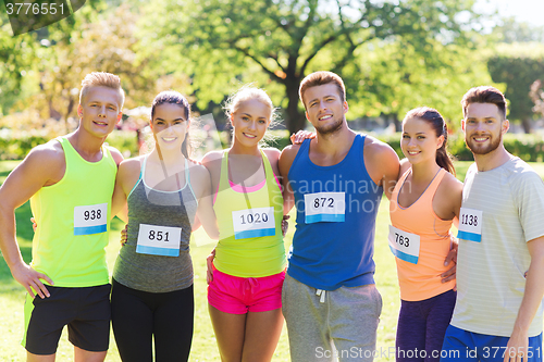 Image of happy friends or couple with racing badge numbers