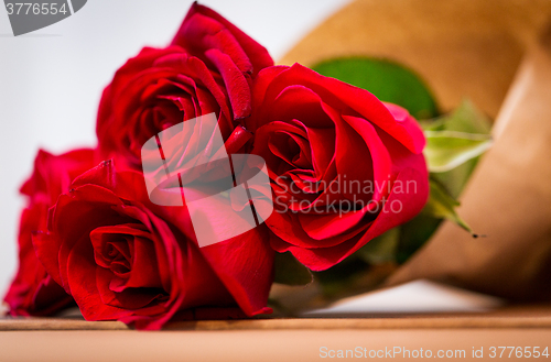 Image of close up of red roses bunch wrapped into paper
