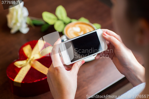 Image of close up of hands with smartphone, gift and coffee