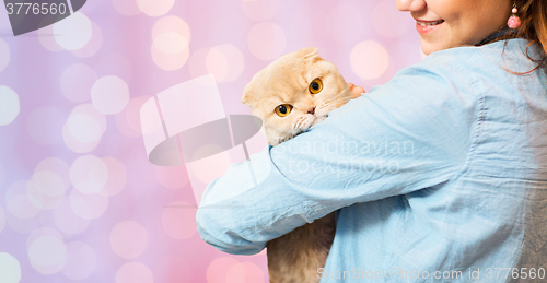 Image of woman holding scottish fold cat over pink lights