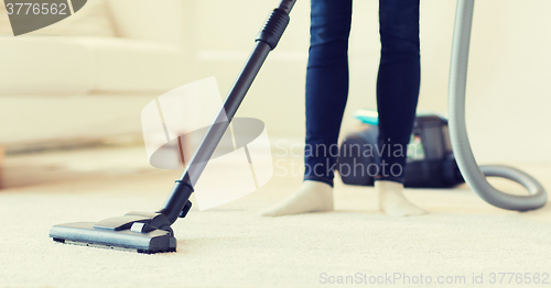 Image of close up of woman legs with vacuum cleaner at home