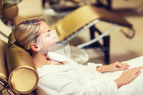 Image of beautiful young woman sitting in bath robe at spa