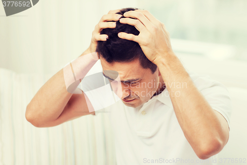 Image of unhappy man suffering from head ache at home