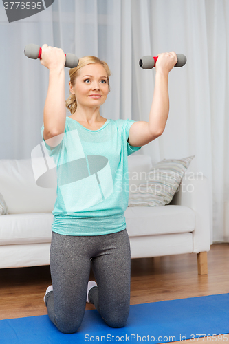 Image of woman exercising with dumbbells on mat at home