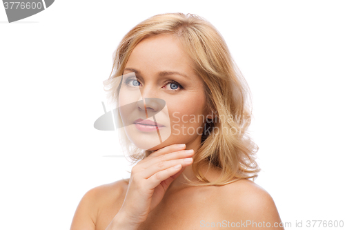 Image of smiling woman with bare shoulders touching face