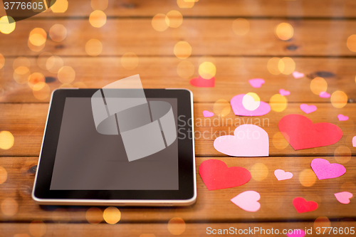 Image of close up of tablet pc and hearts on wood