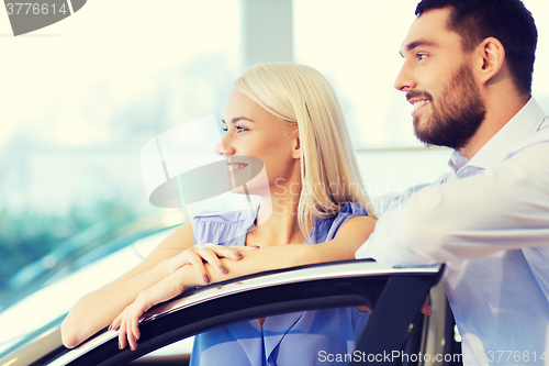 Image of happy couple buying car in auto show or salon