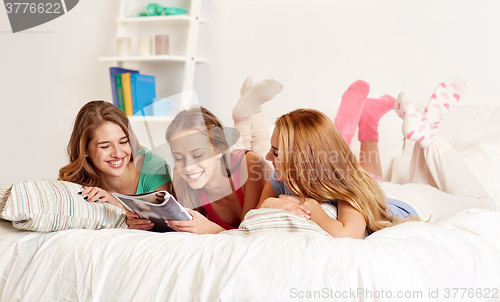 Image of friends or teen girls reading magazine at home