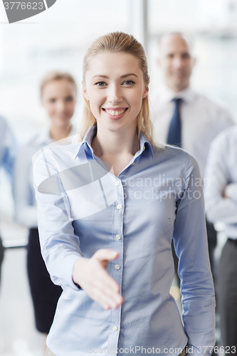 Image of smiling businesswoman making handshake in office