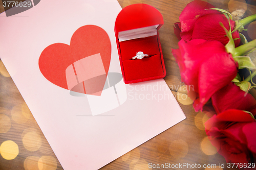 Image of close up of diamond ring, roses and greeting card