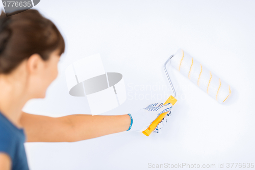 Image of woman with roller and paint colouring the wall