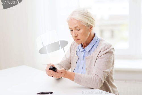 Image of senior woman with glucometer checking blood sugar