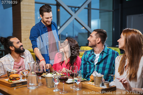 Image of friends dining and drinking wine at restaurant