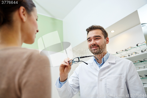 Image of optician giving glasses to woman at optics store